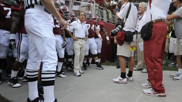 Nick Saban waits with his Alabama football players to run out onto the field.